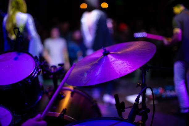 close up on percussionist hitting the cymbal with the band out of focus beyond.